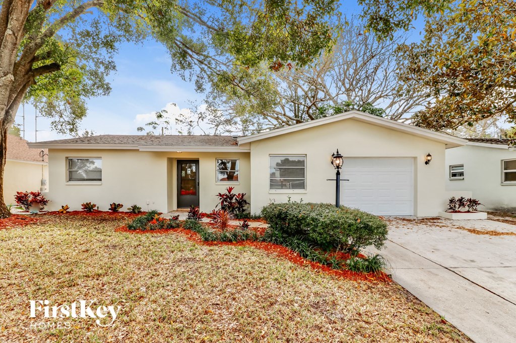 a white house with a driveway and a tree