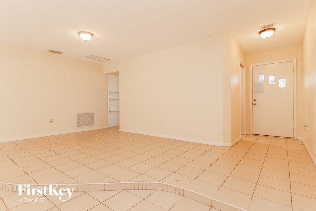 an empty living room with a door to the closet and a tiled floor