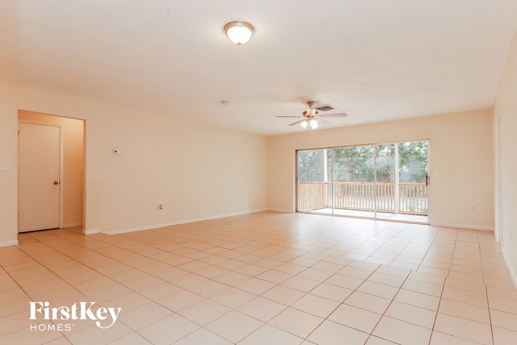 an empty living room with a sliding glass door to a balcony