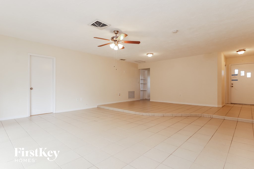 an empty living room with a ceiling fan