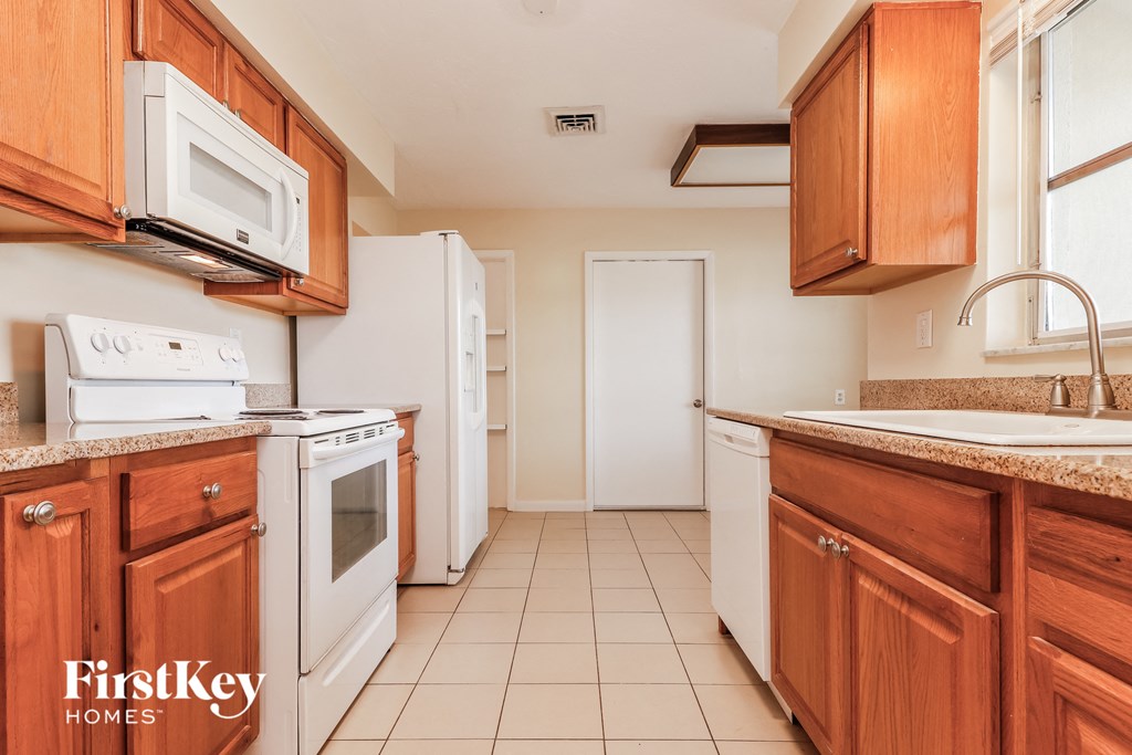a kitchen with wooden cabinets and white appliances and a sink