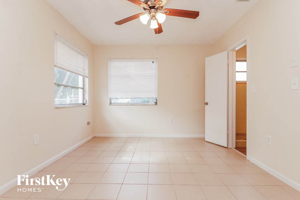 an empty living room with a ceiling fan and a window