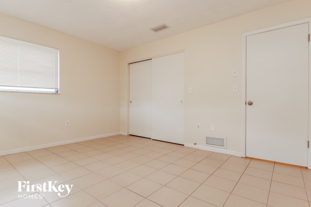 a living room with a tiled floor and a door to a closet