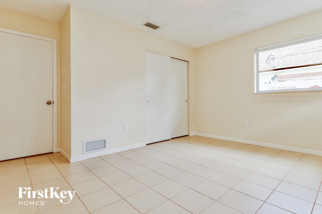 an empty living room with a door to a closet and a window