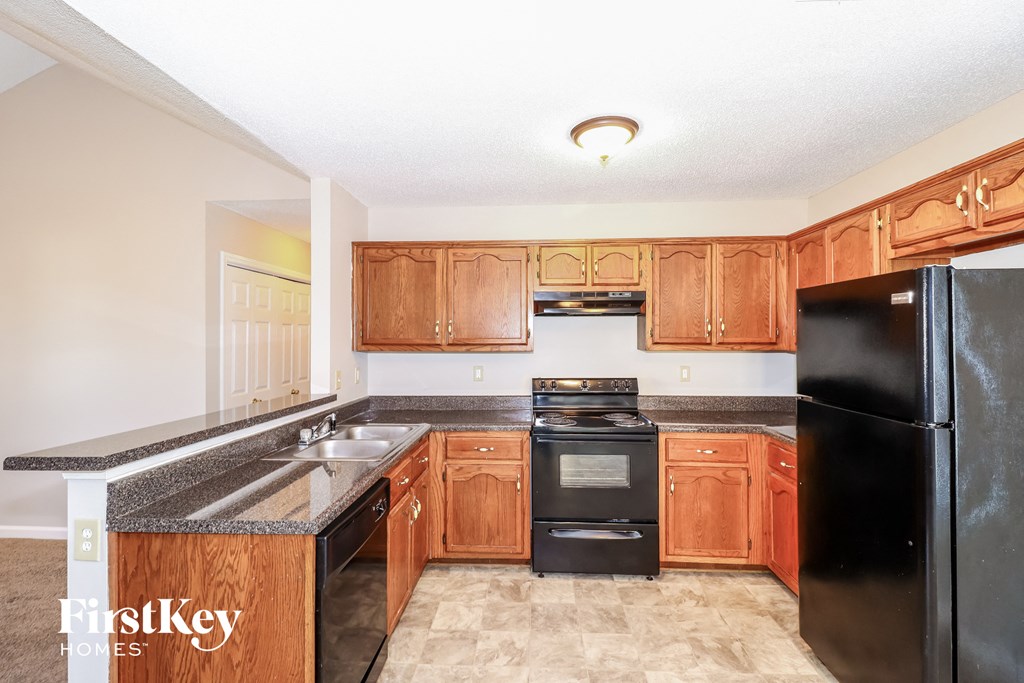 a kitchen with wood cabinets and black appliances and a sink