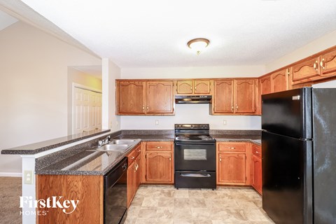 a kitchen with wood cabinets and black appliances and a sink