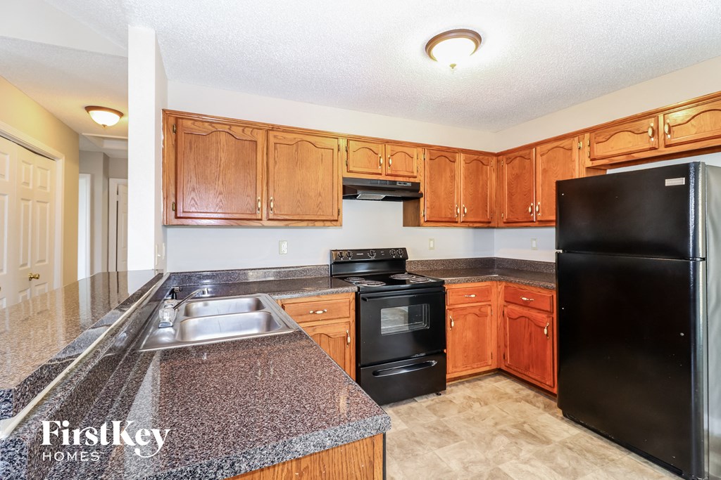 a kitchen with wood cabinets and black appliances and granite counter tops