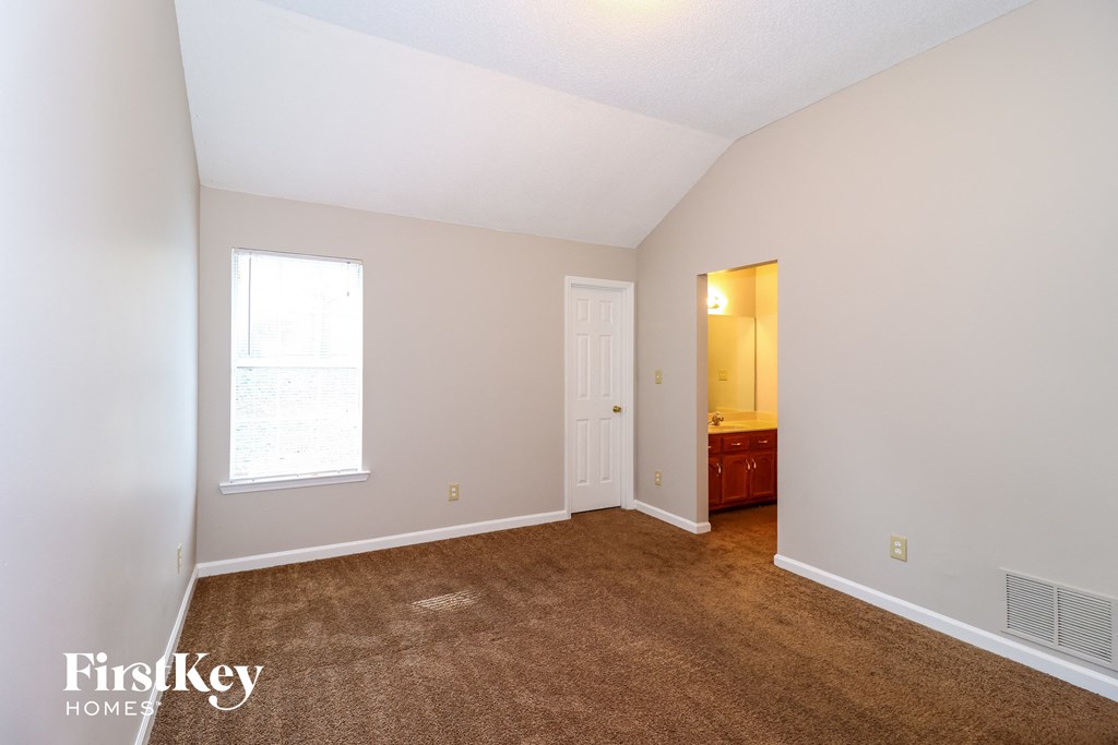 a bedroom with a carpeted floor and a door to a bathroom