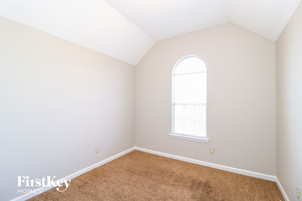 a bedroom with white walls and carpet and a window