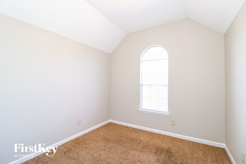 a bedroom with white walls and carpet and a window