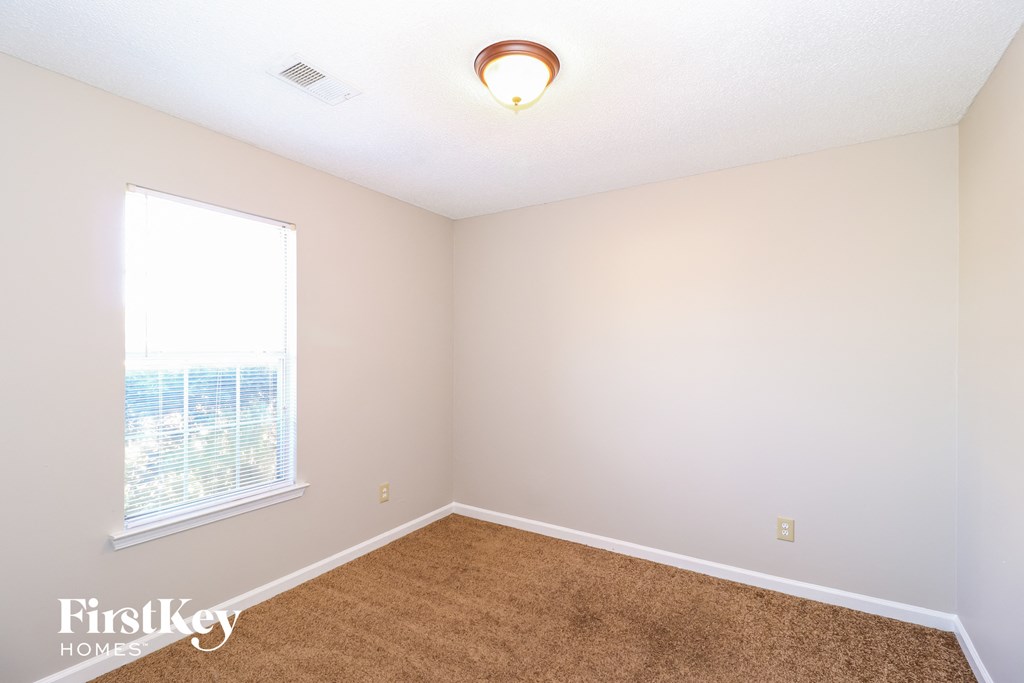 a bedroom with a large window and a brown carpet