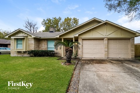 A house with a garage and a tree in front of it.