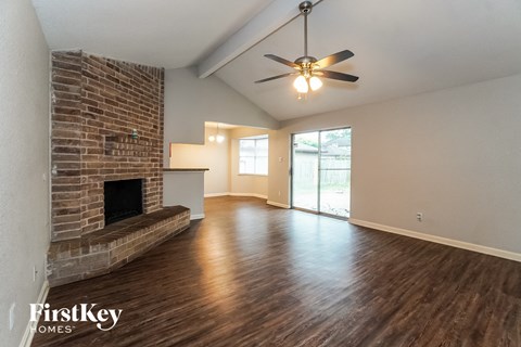 A room with a brick fireplace and wooden floors.