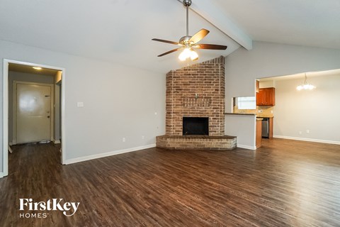 A room with a brick fireplace and a ceiling fan.