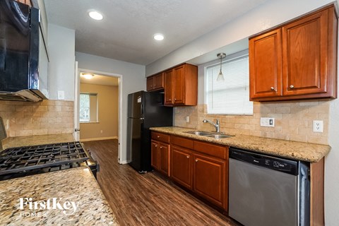 A kitchen with wooden cabinets and a black dishwasher.