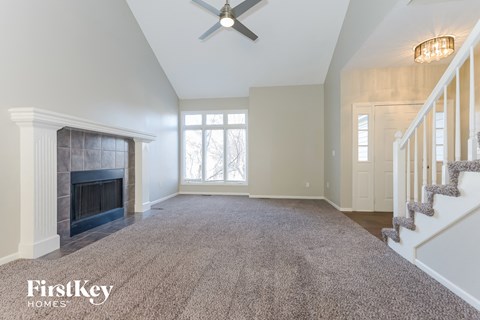 an empty living room with a fireplace and a staircase