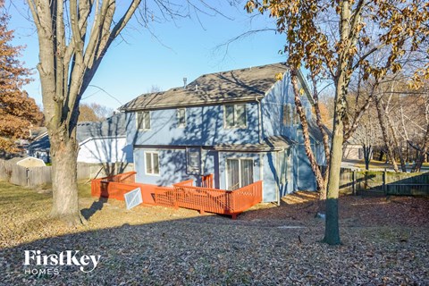 a blue house with a red fence and trees