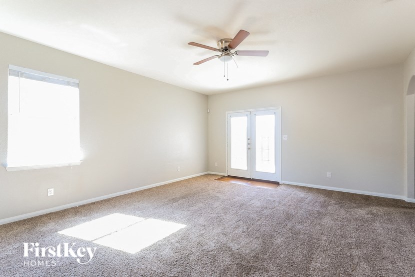 a living room with carpet and a ceiling fan