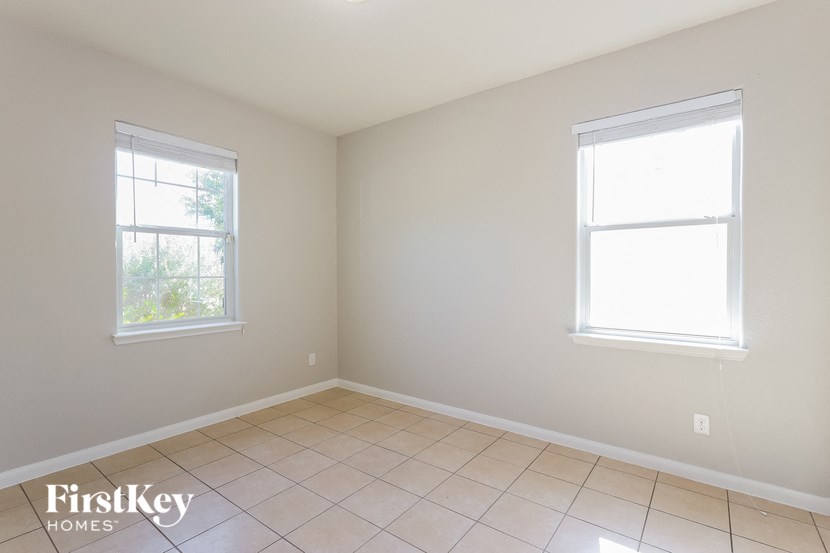 an empty room with two windows and a tiled floor