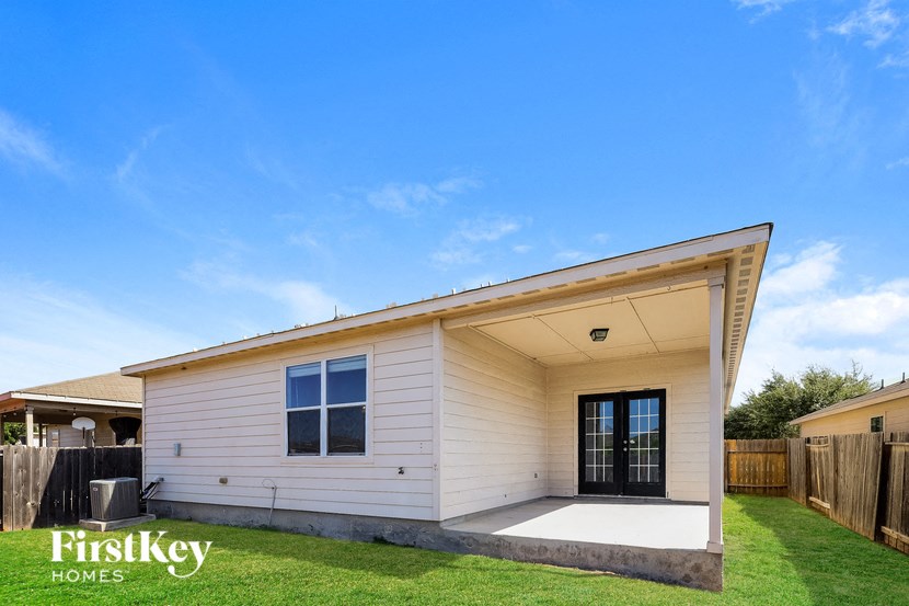 the exterior of a small white house with a porch and grass
