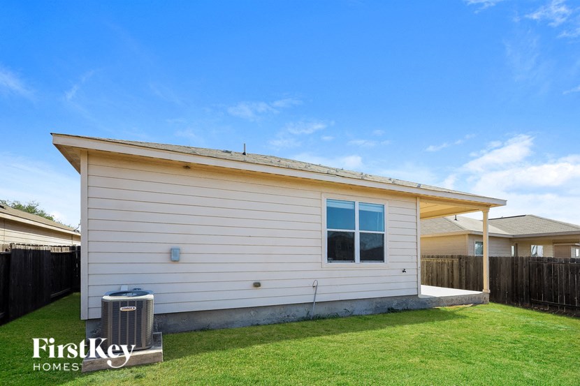 a small white house with a yard and a trash can