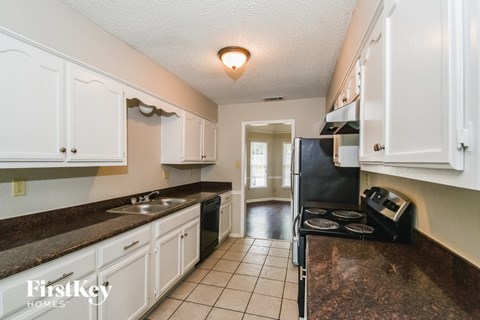 A kitchen with white cabinets and a black fridge.