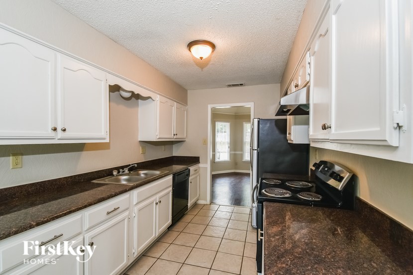 A kitchen with white cabinets and a black fridge.