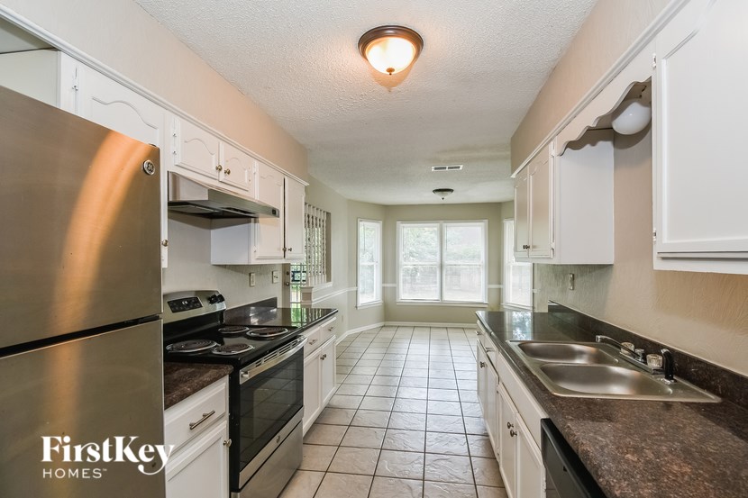 A kitchen with a stainless steel refrigerator and white cabinets.