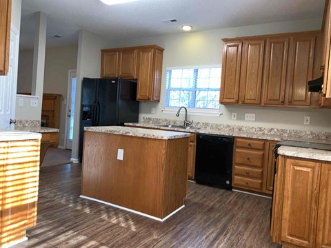 A kitchen with wooden cabinets and a black refrigerator.