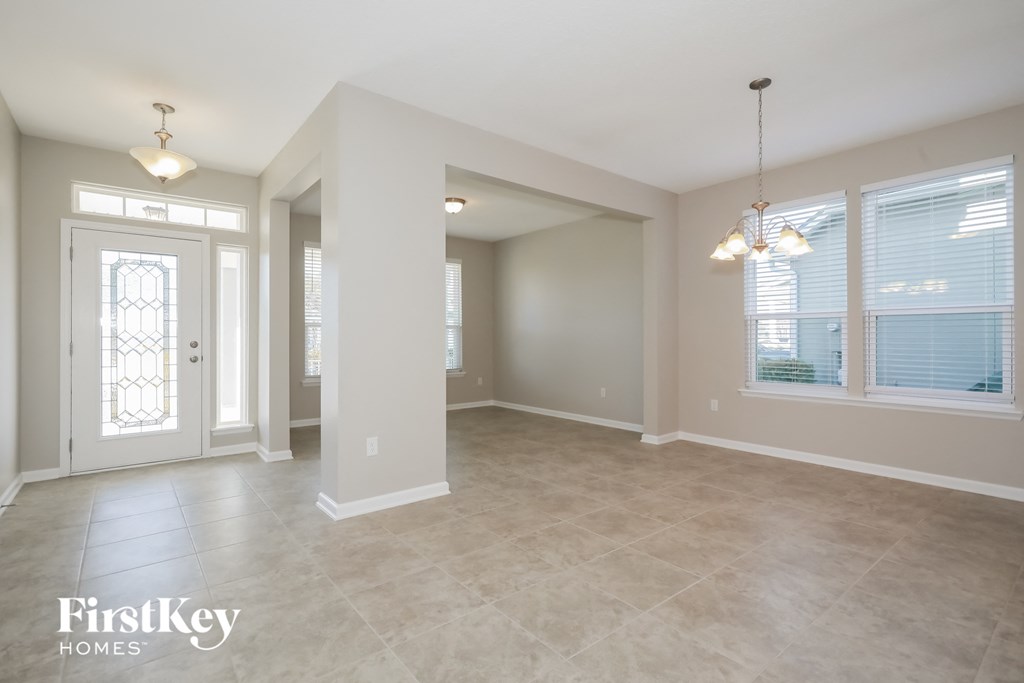an empty living room with a white door and windows