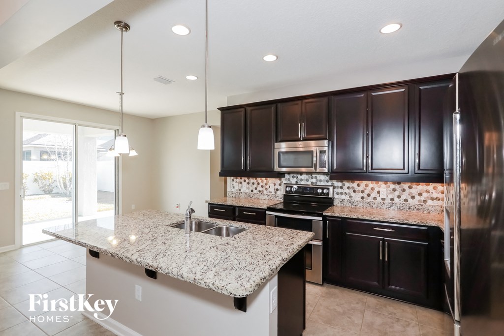 a kitchen with black cabinets and granite counter tops and a sink