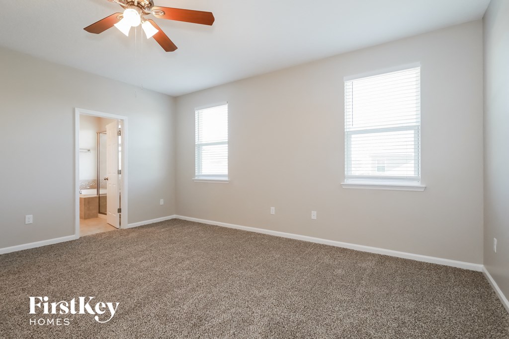 a bedroom with a carpeted floor and a ceiling fan