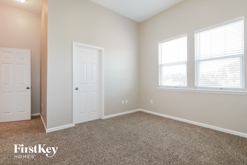 a bedroom with a carpeted floor and two windows