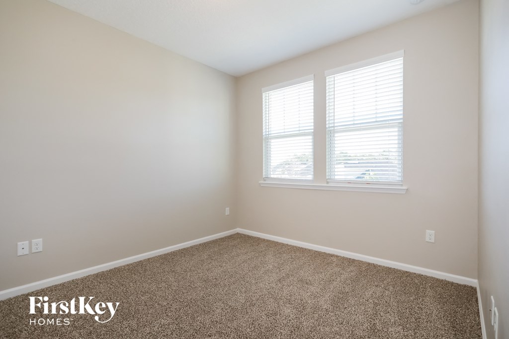 a bedroom with a carpeted floor and two windows