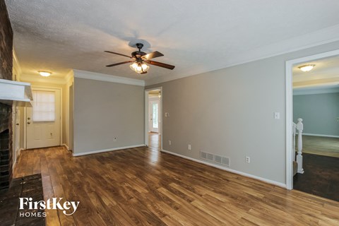 the living room and dining room with wood floors and a ceiling fan