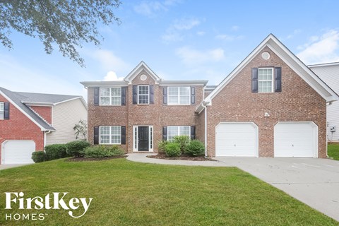 a brick house with white garage doors and a lawn