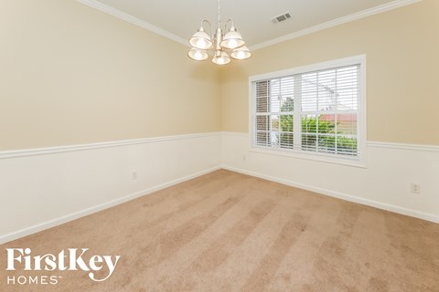 a empty dining room with a window and a chandelier