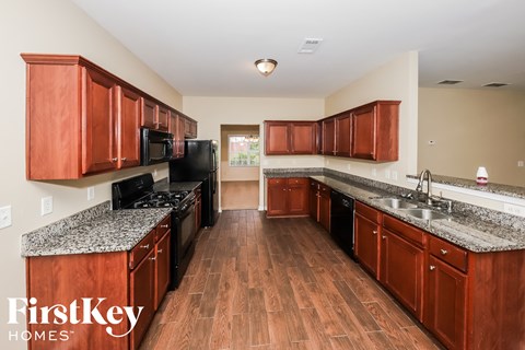 a kitchen with wooden cabinets and granite counter tops and black appliances
