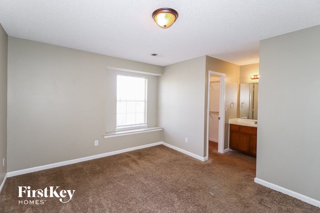 A bedroom with a carpeted floor and a window.