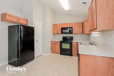 a kitchen with wood cabinets and black appliances and white countertops