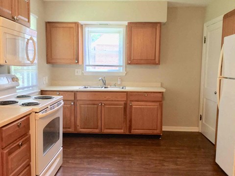 A kitchen with wooden cabinets and a white stove top oven.
