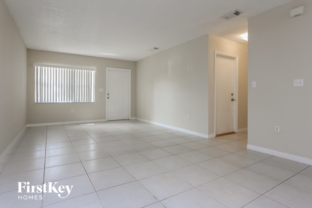 an empty living room with a white tiled floor and a closet