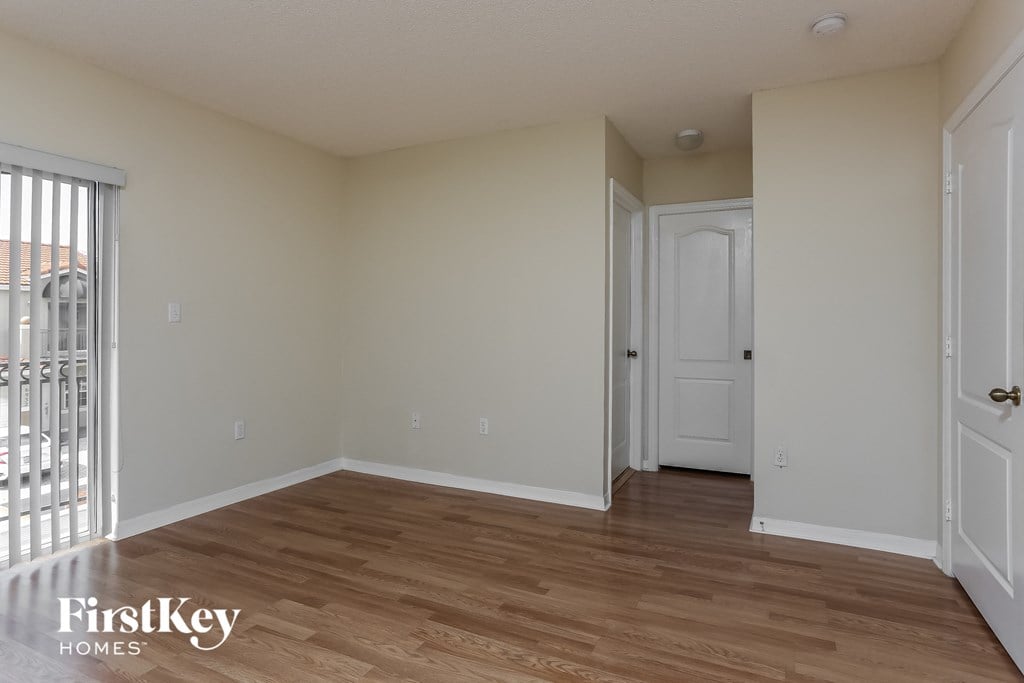 the living room of an apartment with wood flooring and a balcony