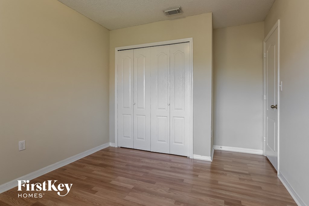 a bedroom with a white door and a wooden floor