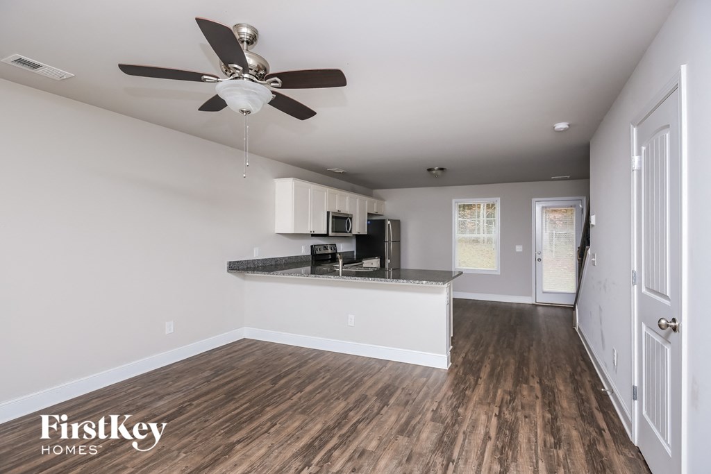 a living room with a kitchen and a ceiling fan