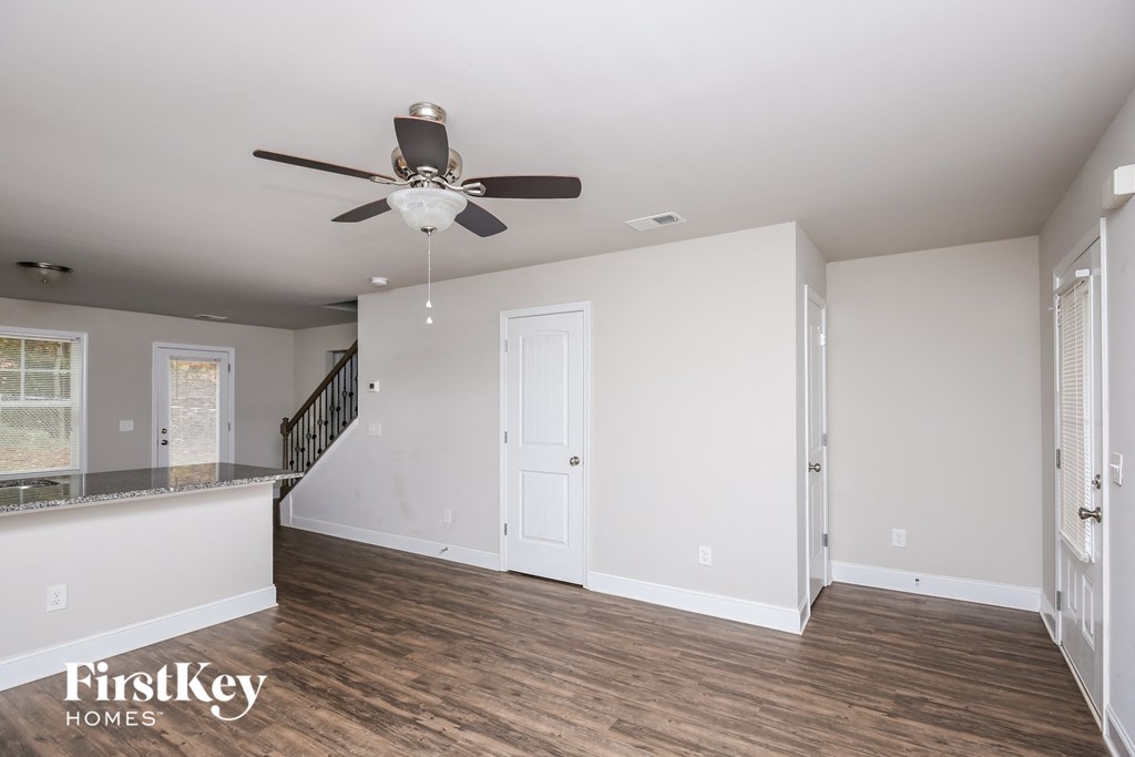 a living room with white walls and a ceiling fan