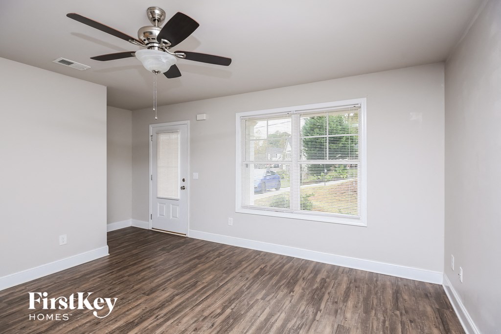 the living room of an empty house with a ceiling fan