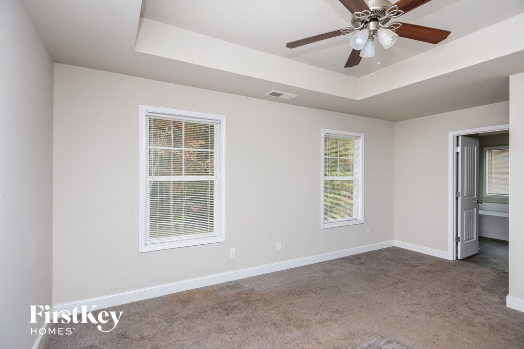 a living room with a ceiling fan and two windows