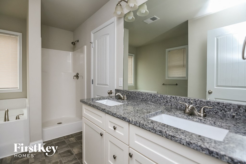 a bathroom with white cabinets and granite counter tops