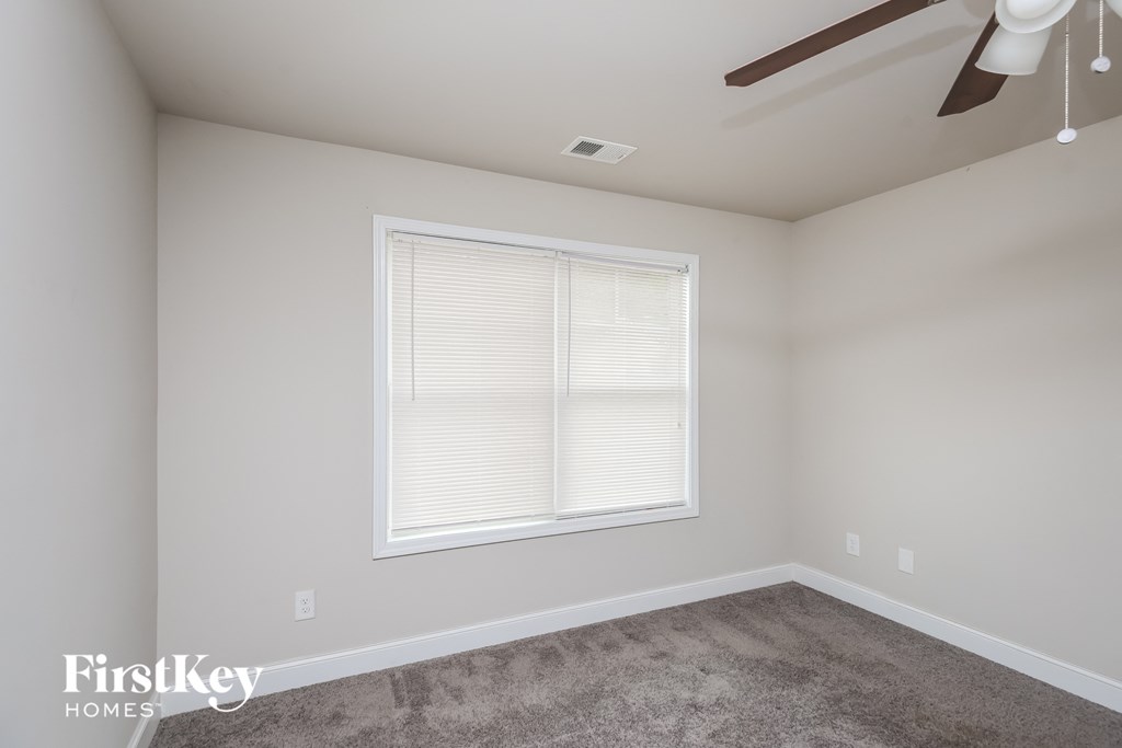 a bedroom with a large window and a ceiling fan